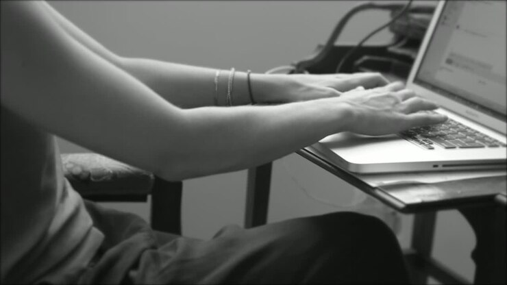 black and white video of a woman typing on a laptop keyboard whilst working her day job