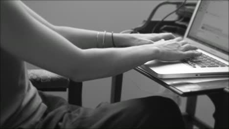 black and white video of a woman typing on a laptop keyboard whilst working her day job