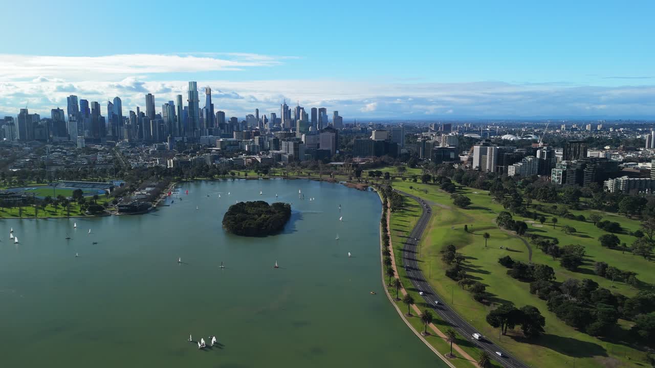 Drone view of cars driving around Melbourne F1 Grand Prix track on clear sky day