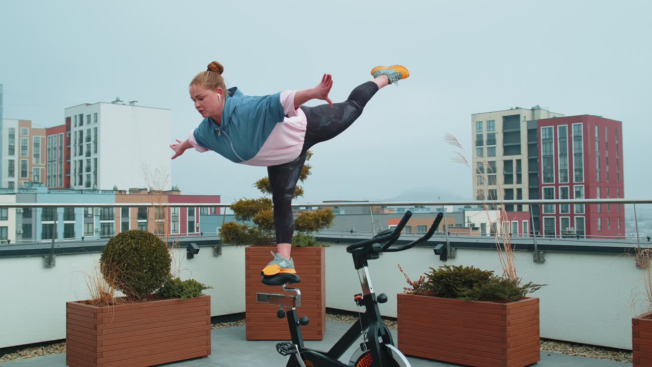 집 지붕 위에 자전거를 타고 고정 된 자전거에서 스 아크로바틱 트릭 연습을 수행하는 운동 소녀