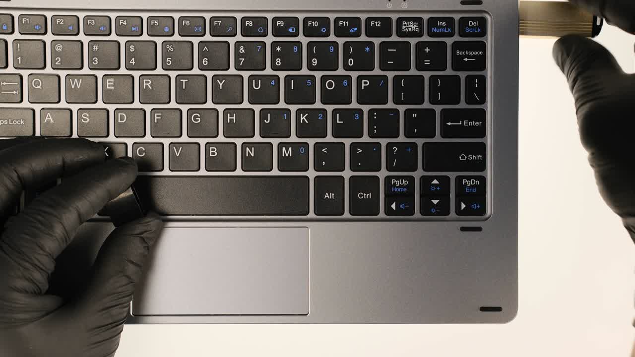 해커는 플래시 드라이브에 데이터를 입하고 복사하고 검은 장갑을 입은 노트북에서 타이핑합니다.