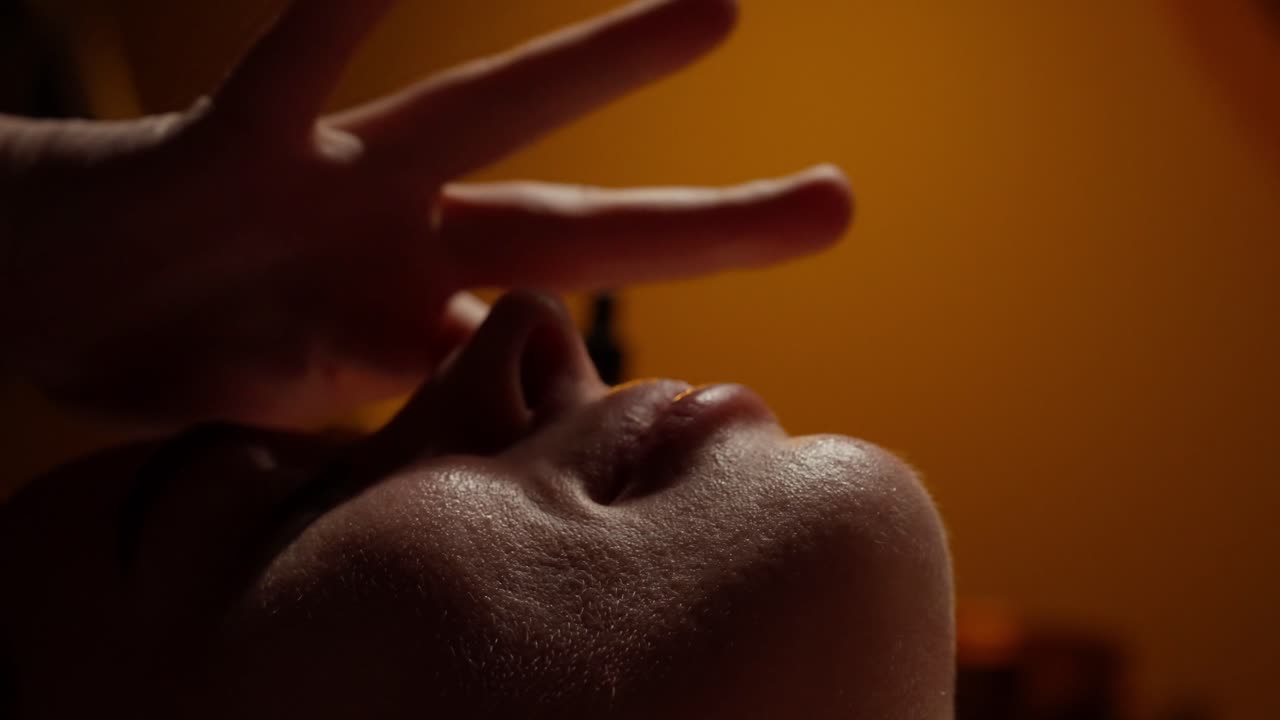 Primo piano di mano che pratica guarigione energetica Reiki sul viso di una donna