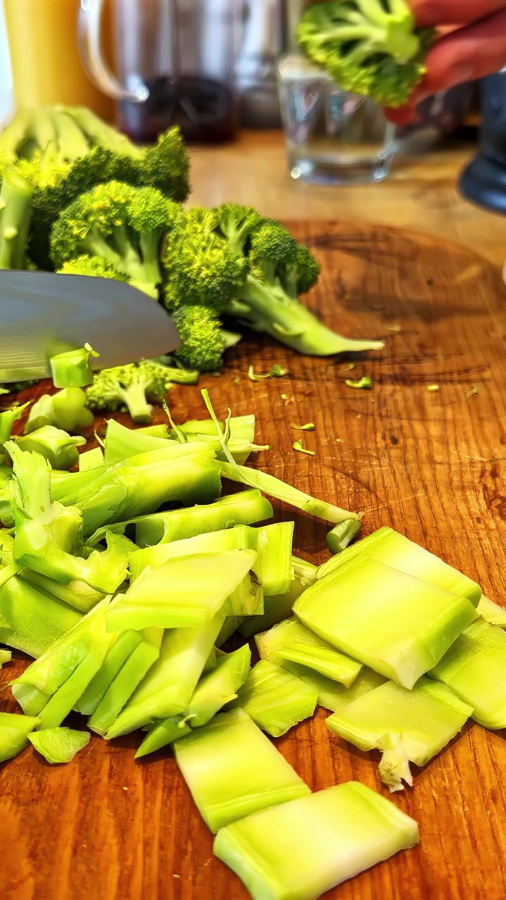 Broccoli freschi e verdi strappati a mano e preparati su un tagliere di legno in un ambiente cucina. Video verticale, ideale per i social media.