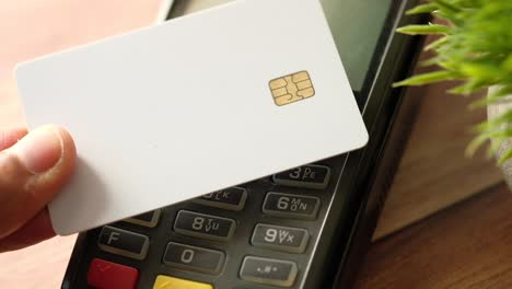 hand holding credit card near payment terminal