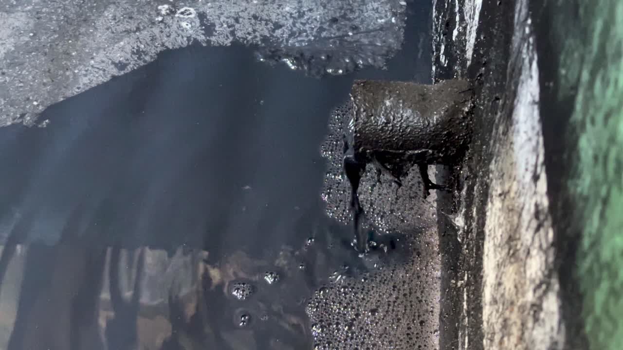 Dark hazardous liquid coming out from pipe to the pond