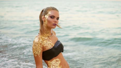 Schöne-Frau-Mit-Professionellem-Goldenem-Make-up,-Die-Im-Wasser-Am-Strand-Steht-Und-In-Die-Kamera-Schaut.-Sexy-Verführerisches-Model