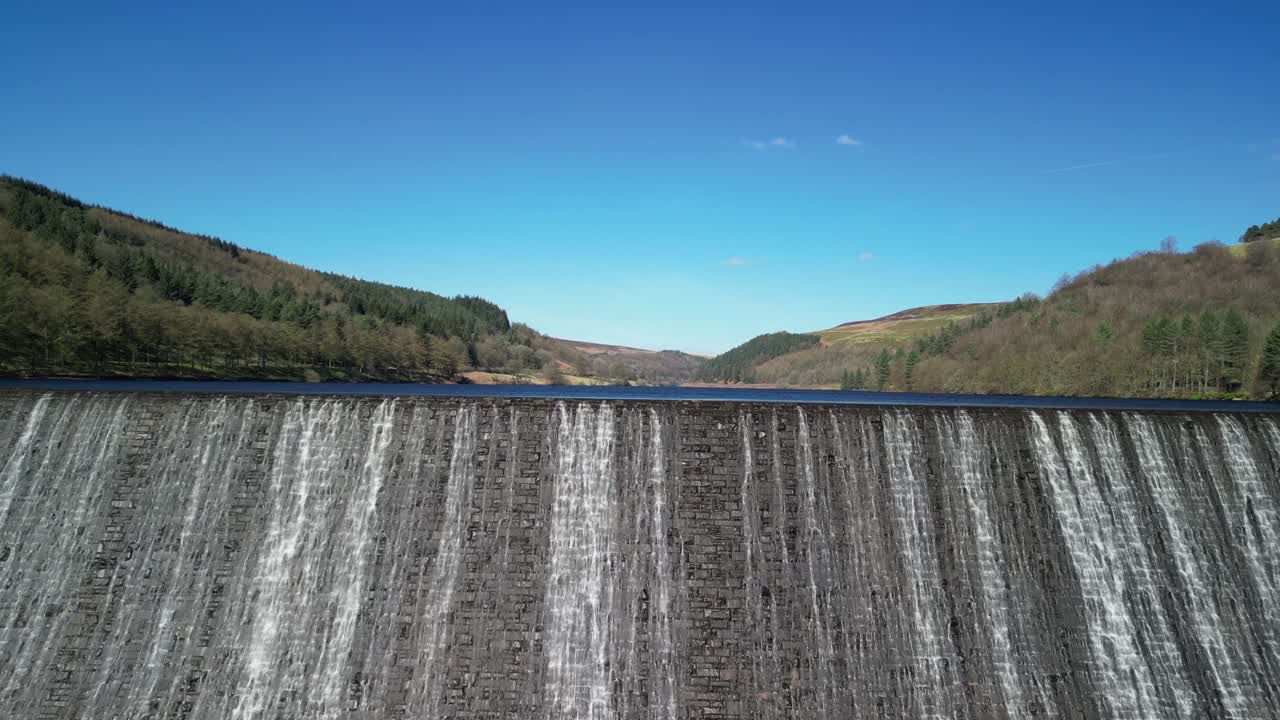 Dramatic aerial rising establishing shot of water cascading over the Derwent Dam, Peak District, UK, home of the Dam Busters practice during the second world war