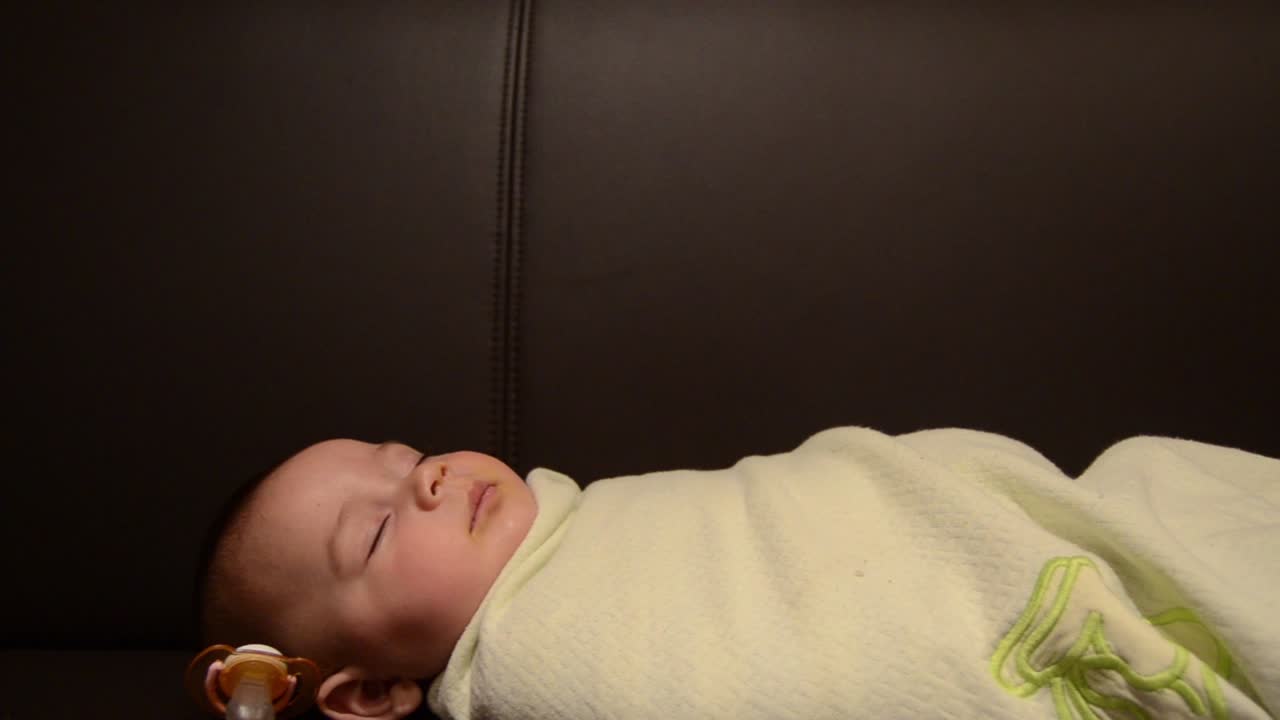 Tracking shot of six months old baby sleeping wraped in blanket