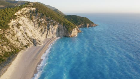 vista aérea de la hermosa playa de milos de lefkada, isla jónica, grecia. puesta de sol luz dorada y olas prístinas rompiendo el mar azul turquesa en la orilla