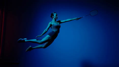 Woman performing badminton jump in blue light