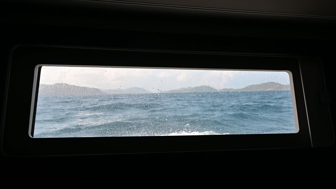 영국령 버진 아일랜드에 있는 50피트 길이의 모노헐 세일링 요트 선실 창밖을 내다보며