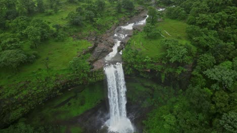 a breathtaking drone view of vasudhara falls in bhandardara, maharashtra, india, surrounded by dense forests and lush green mountains