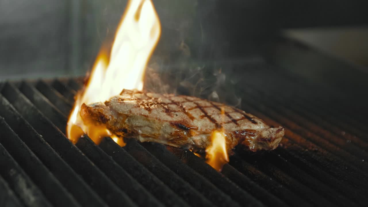 Juicy steak sizzles over open flames on a hot grill
