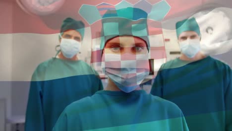 animation of waving croatia flag over portrait of diverse surgeons in surgical masks at hospital