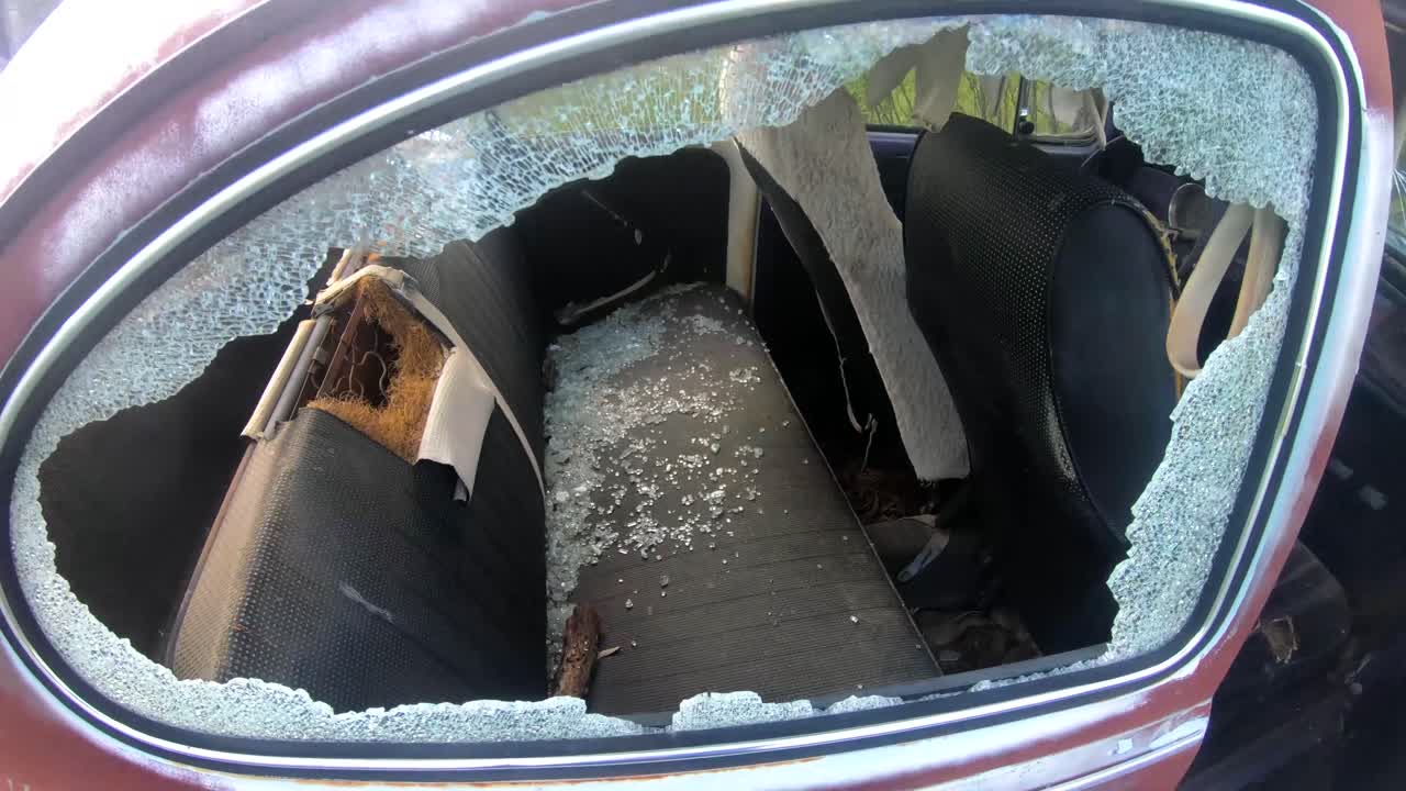 Broken glass on the seats of a old vehicle sitting in the sun.