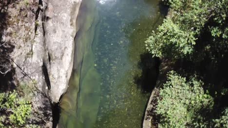 Drone-looks-down-onto-a-crystal-clear-mountain-stream-and-rotates-slowly