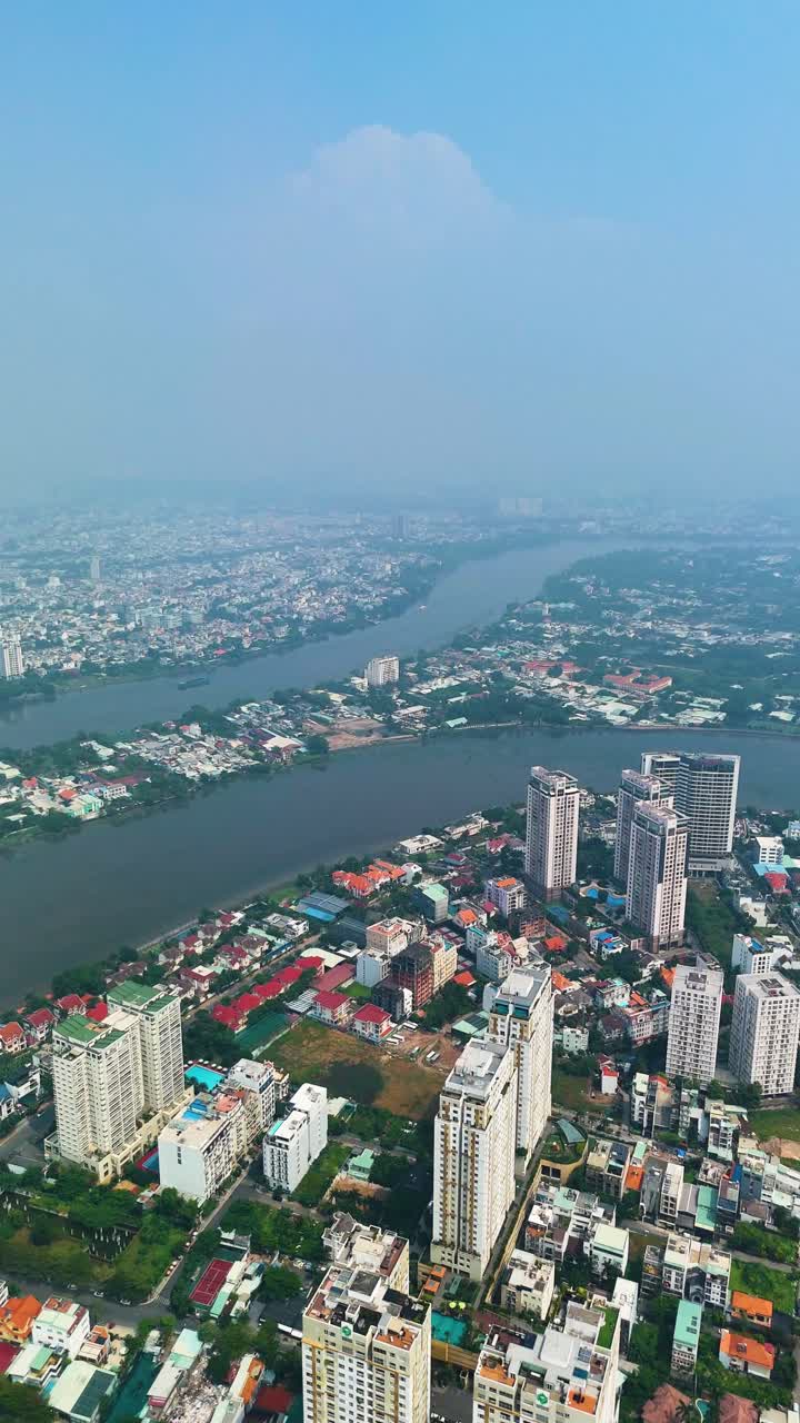 Vertical aerial: apartment buildings near the Saigon River during the day with fog in Ho Chi Minh City, Vietnam.