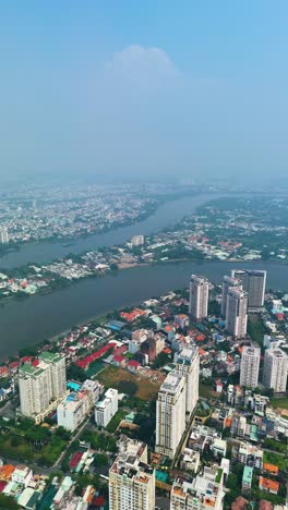 vertical aerial: apartment buildings near the saigon river during the day with fog in ho chi minh city, vietnam.