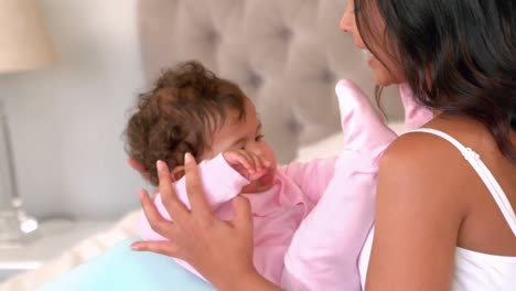 -Mother-playing-with-baby-daughter-on-bed-