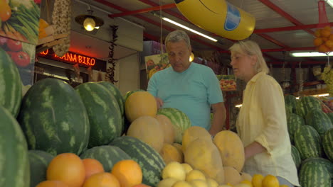 family couple choosing watermelon on street market