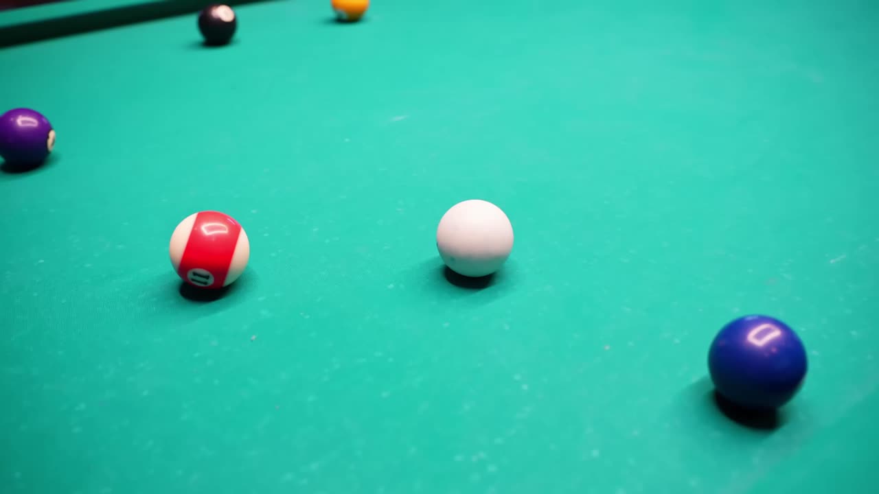 Keu en kleurrijke genummerde poolballen op groen vilt, geringe scherptediepte en zachte barverlichting, een rustige opstelling tonend voor de volgende poolstoot