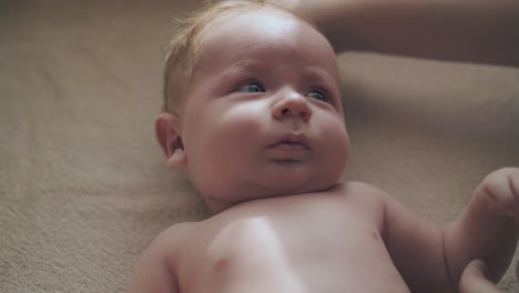 cute newborn boy with big crystal blue eyes lies on table