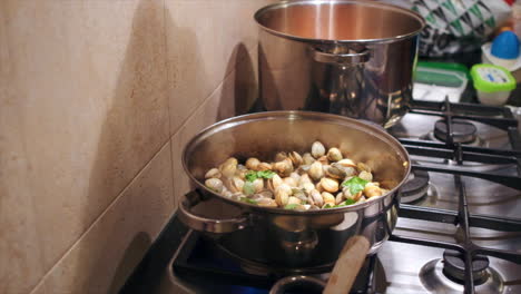 chef adding some fresh parsley into pot of cooking clams in portuguese kitchen