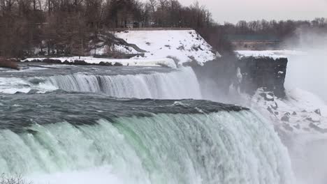 water rushes over niagara falls in winter