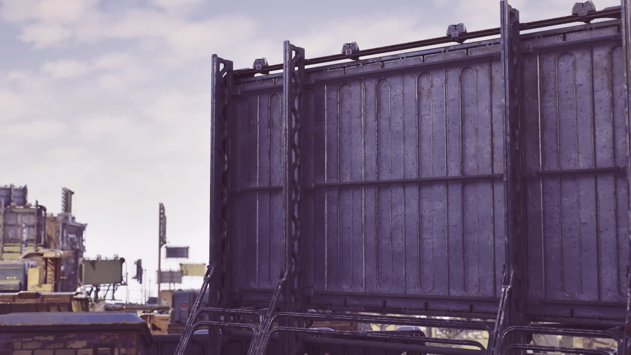 Forladt gård, der fremviser aldrende metalstrukturer og en overskyet himmel.
