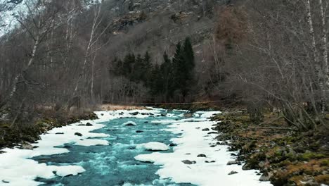 aerial along a frozen river and across a small bridge in norway