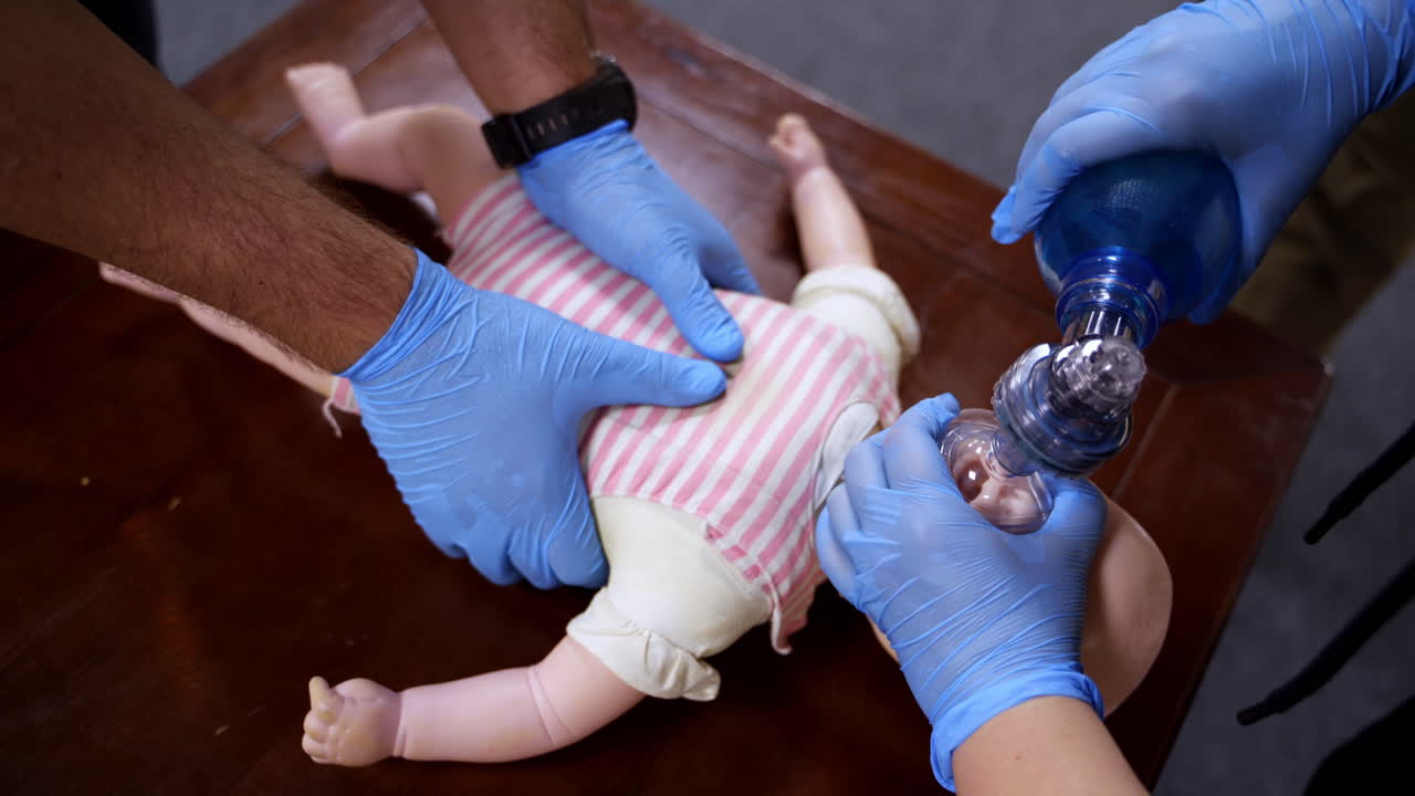 Demonstrating chest compressions on CPR doll. CPR training medical procedure on a dummy child. First aid. Top view.