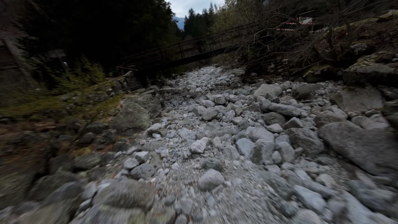 FPV aerea che segue un altro drone sopra rocce e alberi in Val Masino, Italia