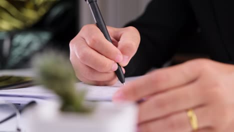 close up of business woman hands writing a business document at workplace.