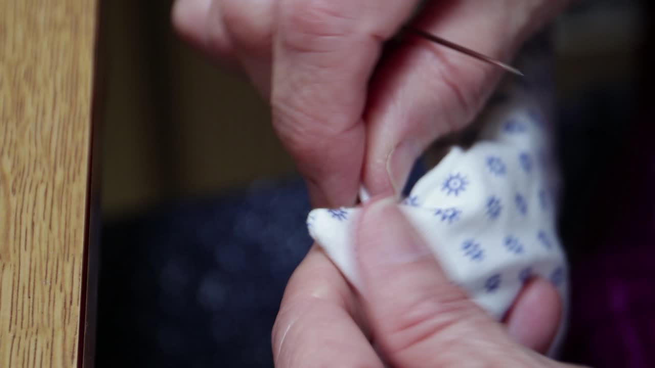A seamstress cutting a hole through the thread to insert an elastic to finish the face mask - close up