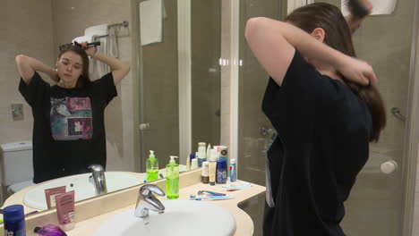 woman brushing hair in hotel bathroom