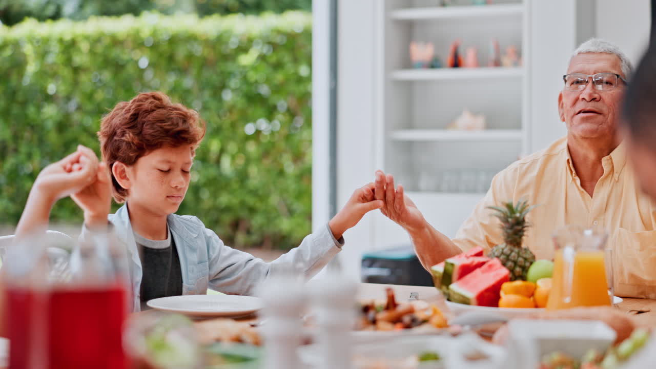 Famiglia, mani che si tengono e preghiera a pranzo
