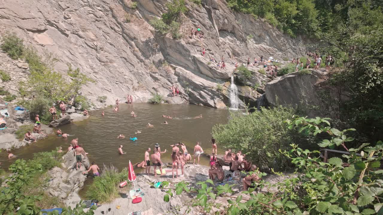 People swimming and relaxing at a natural waterfall and swimming hole