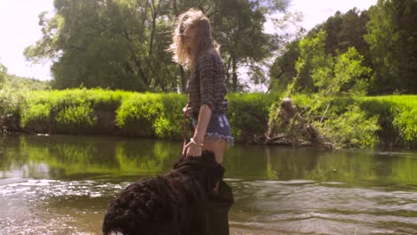 young woman with a dog walking through the river