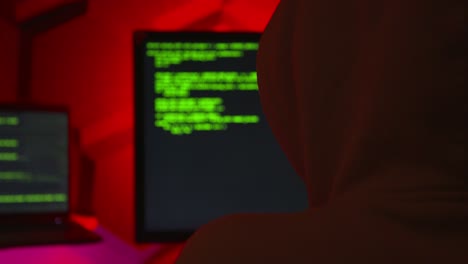 anonymous hacker writing code in a red room