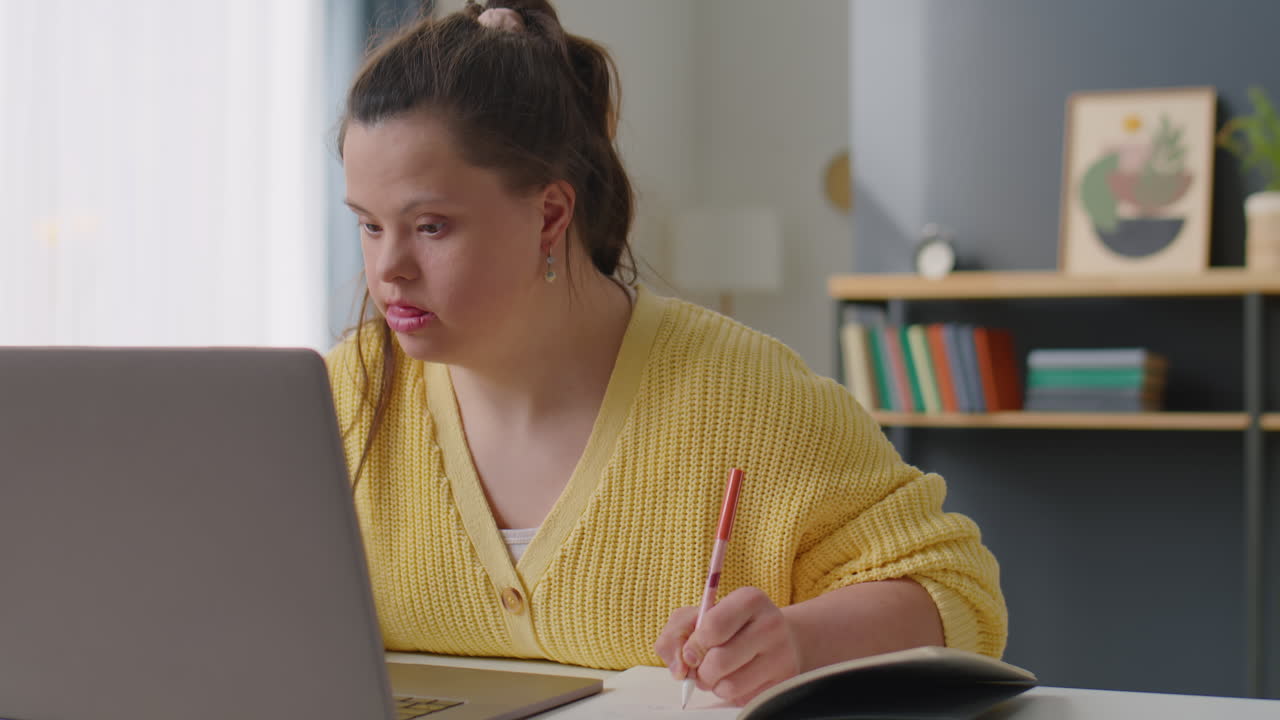 Girl with Down Syndrome Taking Notes and Typing on Laptop