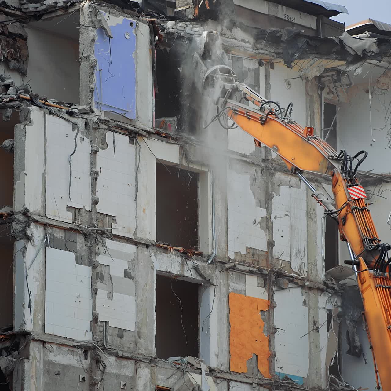 Dismantling the destroyed roof of a high building. Excavator grabber reaches high to demolish the house
