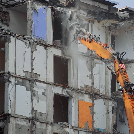 dismantling the destroyed roof of a high building. excavator grabber reaches high to demolish the house