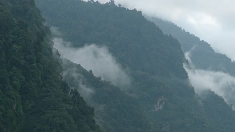 low lying clouds in himalayas mountains in nepal, elevated aerial shot from above of clouds over misty forest in himalayas mountains in nepal