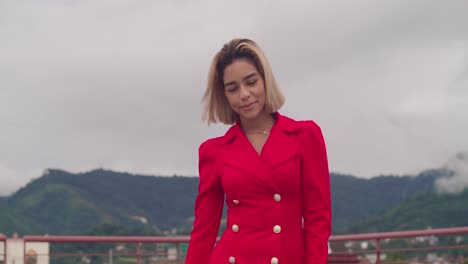 A-rooftop-in-Port-of-Spain,-Trinidad,-provides-the-setting-for-a-young-Hispanic-girl-walking-in-a-red-dress,-with-tall-buildings-as-the-backdrop