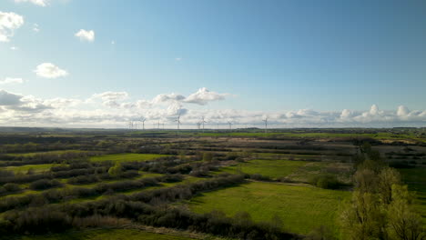 Langsamer-Vorwärtsflug-Aus-Der-Luft,-Der-Bei-Sonnenuntergang-Einen-Großen-Windmühlen-Turbinenpark-Am-Horizont-Zeigt