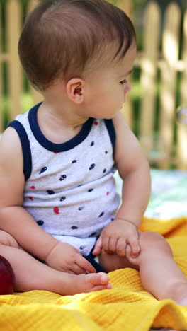 little baby boy watching the soap bubbles fly. cute calm caucasian child sitting in the garden in summer. blurred backdrop. vertical video