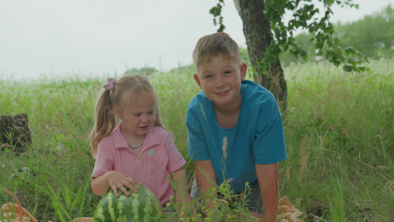 Children enjoying summer time playful teasing, Joyful sibling interaction in sunny outdoor environment, Lively scene of brother teasing sister with watermelon and nature surroundings