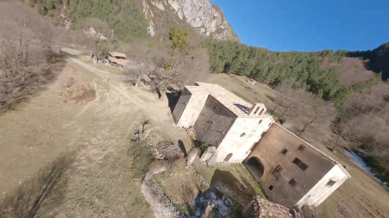 Dron FPV volando sobre un antiguo edificio de villa y paisaje natural en Cataluña