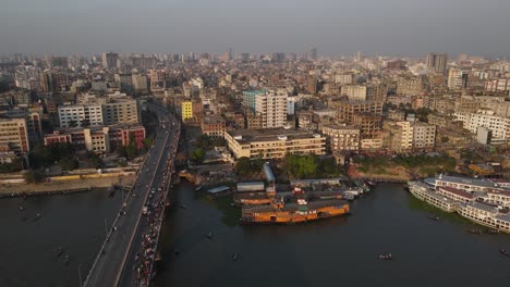 Vista-Aérea-De-La-Ciudad-De-Dhaka-Con-Puente-Sobre-El-Río-Buriganga-A-Lo-Largo-De-La-Estación-De-Vapor-De-Cohetes-De-Paletas-Y-La-Terminal-De-Ferry