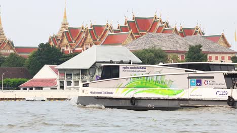 ferry moves past temple on bangkok's river